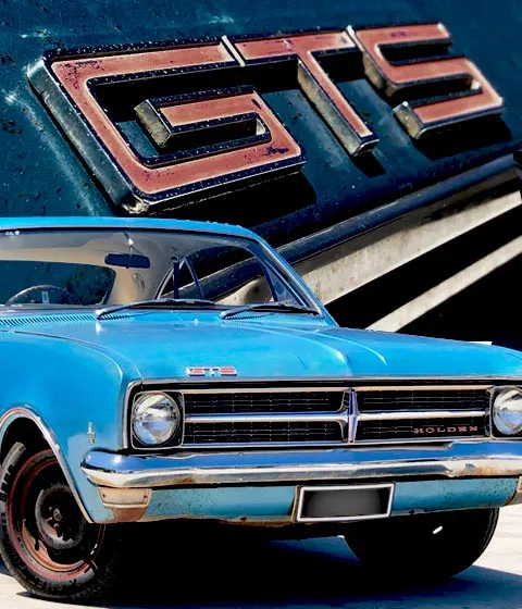 Light blue Holden Monaro GTS coupe front with a close-up of its red GTS badge behind