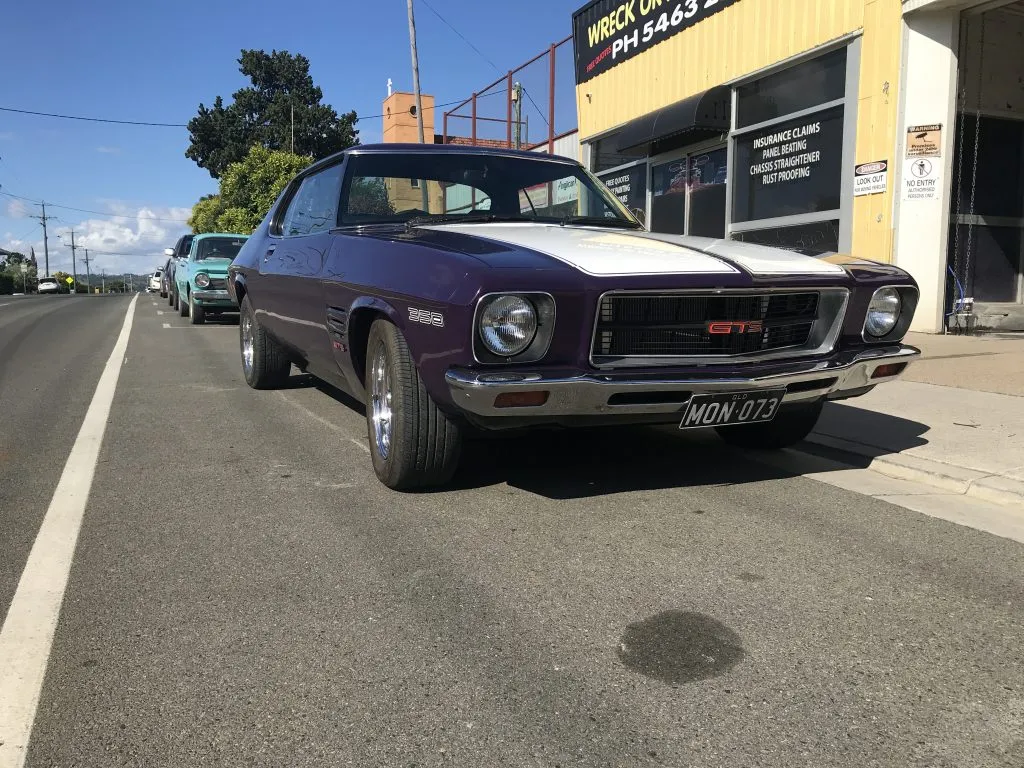 Purple Holden Monaro GTS coupe with a white bonnet stripe parked on a street