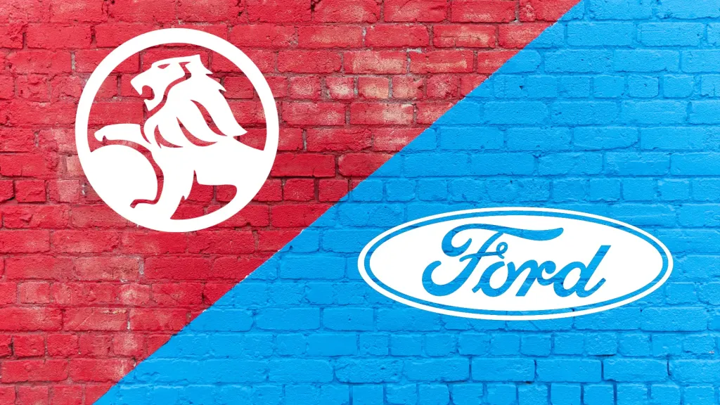 Holden lion logo on a red brick wall facing the Ford oval logo on a blue brick wall