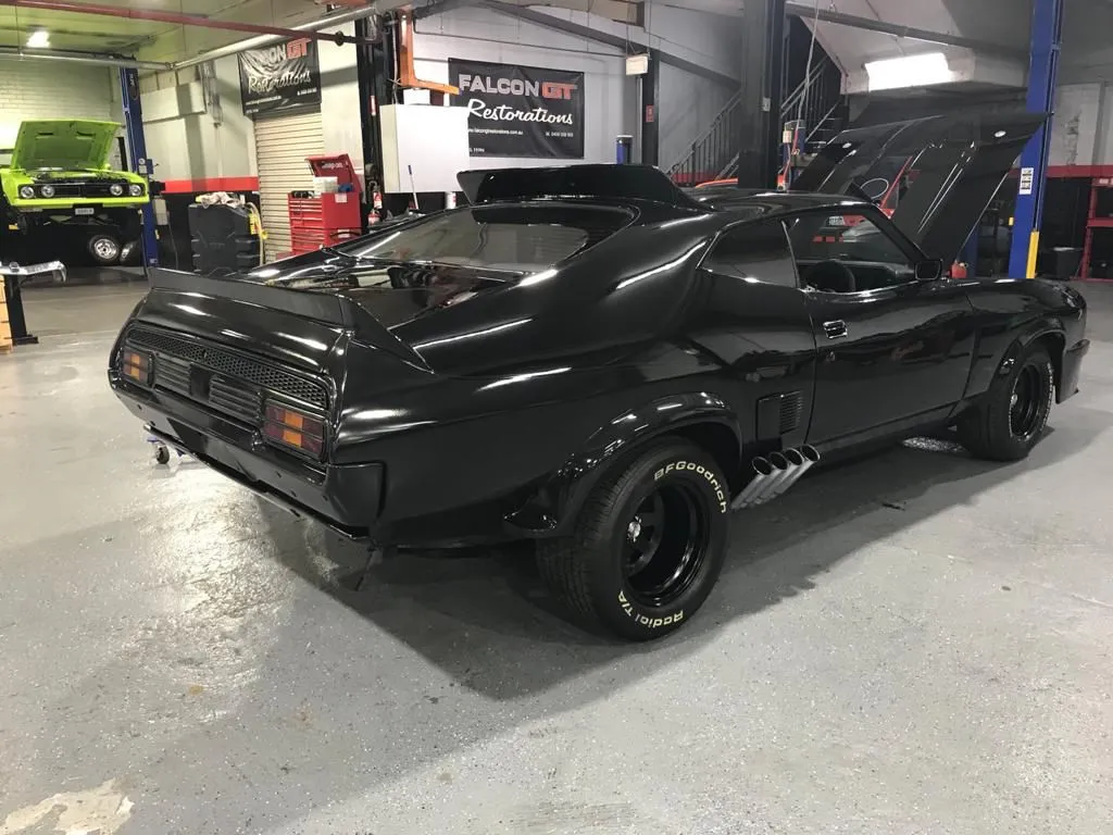 Rear three-quarter view of the black Interceptor replica with side pipes and spoilers in a workshop