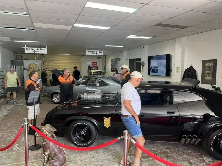 Visitors and staff on the museum floor around the black Interceptor replica behind red ropes