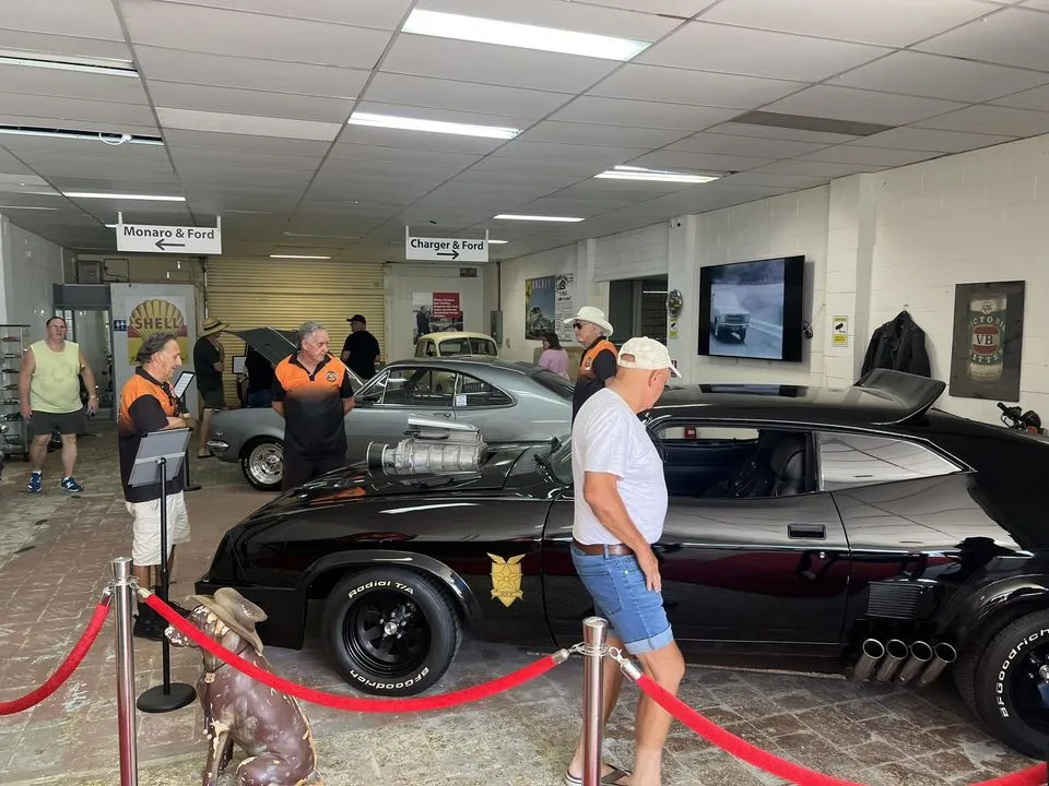 Visitors and staff on the museum floor around the black Interceptor replica behind red ropes