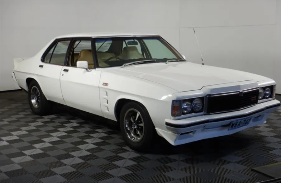 White Holden Monaro GTS four-door sedan with tan interior and alloy wheels on a chequered floor